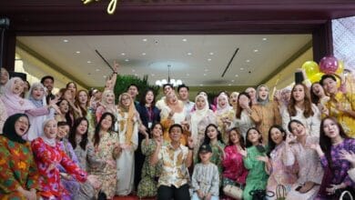 bayu somerset 2 - Wilayah.com.my Large group of people in colorful traditional outfits posing together for a group photo in front of a Bayu Somerset storefront, celebrating together.