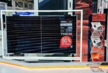 Large solar panel display at an expo booth, framed by a white illuminated frame, showing 'TNC 3.0' and a red '90% Bifaciality' badge.