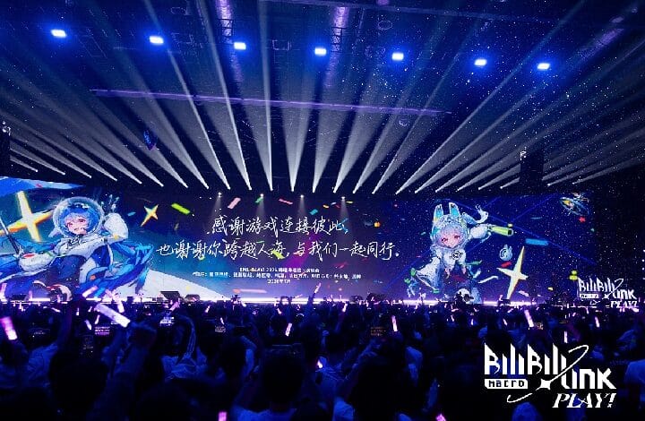 Concert stage with a wide LED screen showing two anime-style characters and Chinese text, crowd waving purple glow sticks under blue stage lights.