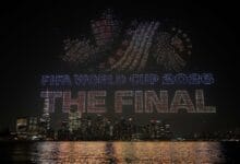 dataran merdeka - Wilayah.com.my Nighttime city skyline with a drone light show spelling 'FIFA World Cup 2026 THE FINAL' over the water.