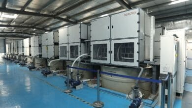 delectrik 2 - Wilayah.com.my Row of large gray industrial machines connected by hoses in a blue-floored factory hall.