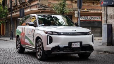 gac - Wilayah.com.my White SUV with colorful promotional wrap parked on a cobblestone city street in front of storefronts.