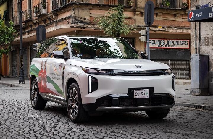 gac - Wilayah.com.my White SUV with colorful promotional wrap parked on a cobblestone city street in front of storefronts.