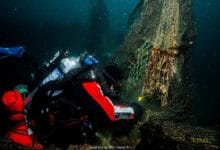 hyundai sea - Wilayah.com.my Underwater scene of a scuba diver in red and black trimming a fishing net tangled around a submerged structure.