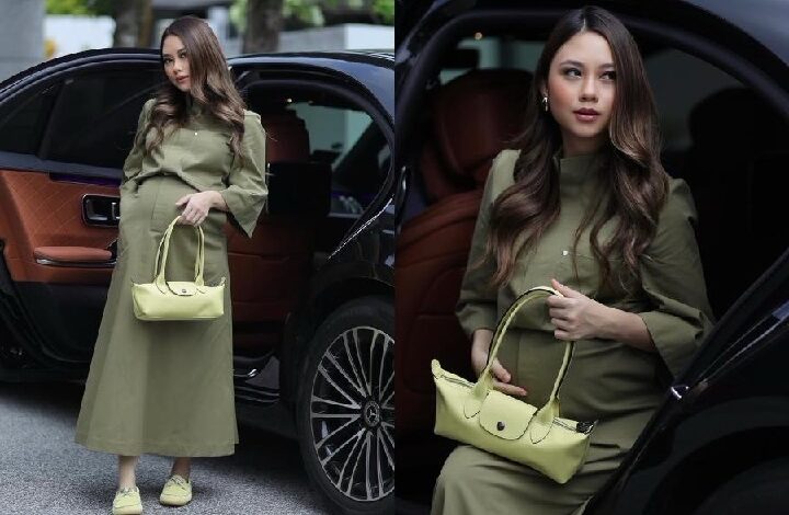 intan najuwa 2 - Wilayah.com.my Model in an olive-green dress stands beside a black car, holding a light yellow handbag.