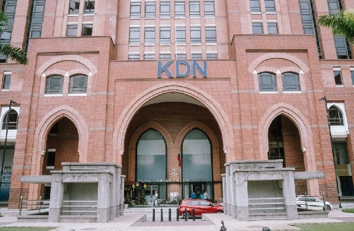 kdn - Wilayah.com.my Brick building with three arched entrances and a blue KDN sign; people near the doors and a red car in front.