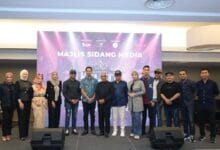 klate artist 2 - Wilayah.com.my Group of men and women standing in a line on a stage in front of a purple backdrop that reads 'Majlis Sidang Media' during a media briefing.