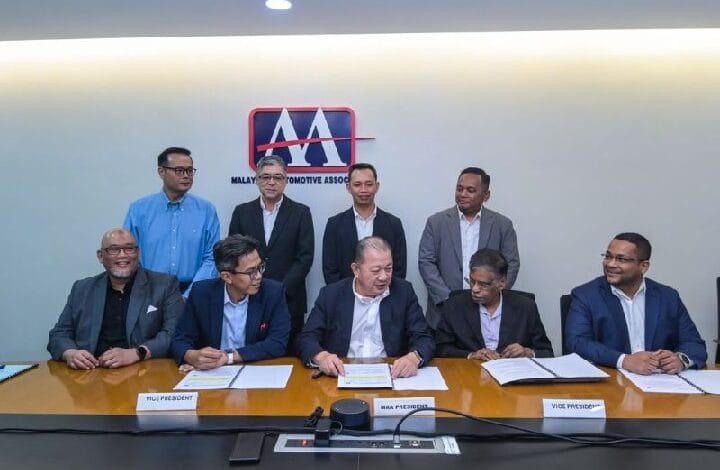 maa - Wilayah.com.my Eight men in business attire sit and stand around a conference table during a signing ceremony; documents and nameplates on the table, with a Malaysian Automotive Association logo on the wall behind them.