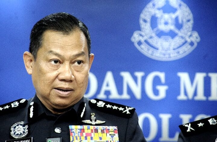 Senior police officer in dress uniform speaking at a press briefing, with ribbons on his chest and a blue backdrop featuring an official emblem