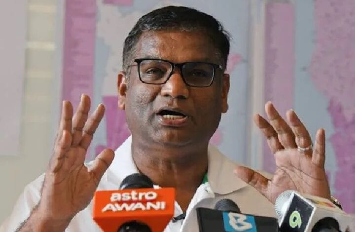 pathmanathan - Wilayah.com.my Man wearing glasses speaks at a press conference, with multiple microphones including Astro AWANI in front of him.