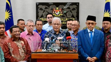 pembangkang 2 - Wilayah.com.my Group of Malaysian officials at a press conference behind a podium with multiple microphones, Parliament of Malaysia signage in the background and Malaysian flags on both sides.