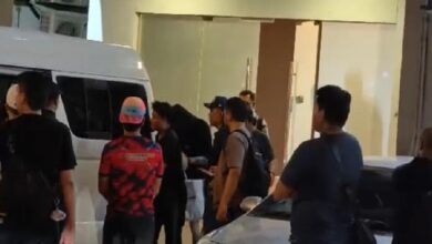 polis - Wilayah.com.my Group of people gathered beside a white van outside a building, some with backpacks and casual clothing.