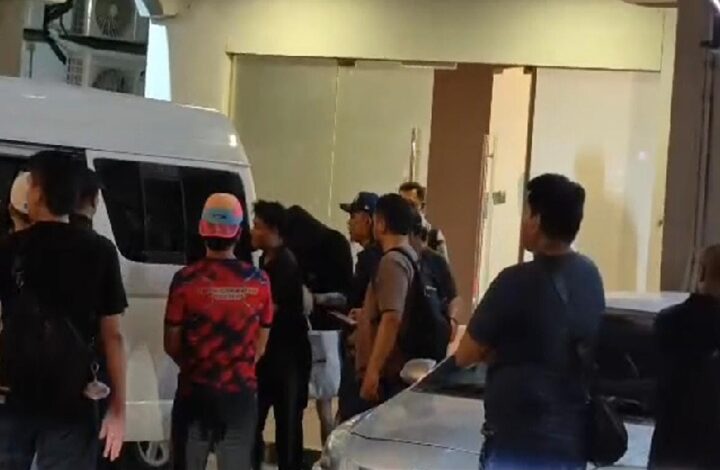 polis - Wilayah.com.my Group of people gathered beside a white van outside a building, some with backpacks and casual clothing.