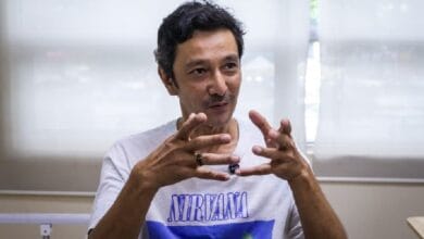 Man wearing a Nirvana t-shirt gesturing with his hands while speaking in a bright room