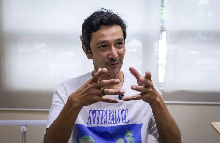 qi razali 2 - Wilayah.com.my Man wearing a Nirvana t-shirt gesturing with his hands while speaking in a bright room