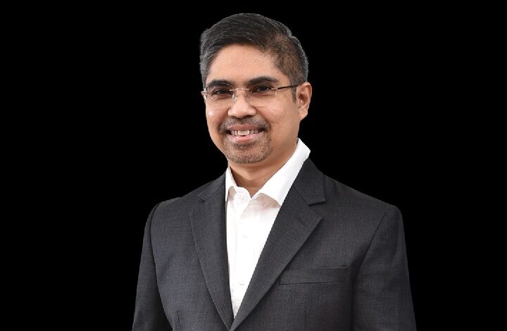 samad majid - Wilayah.com.my Professional man in a dark suit and white shirt, smiling at the camera against a black background.