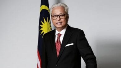 siti nurhaliza - Wilayah.com.my Portrait of a middle-aged man in a black suit and red tie standing beside the Malaysian flag.