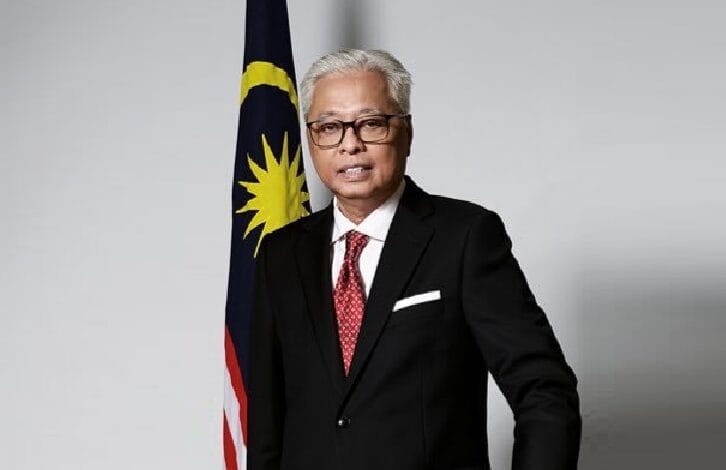 siti nurhaliza - Wilayah.com.my Portrait of a middle-aged man in a black suit and red tie standing beside the Malaysian flag.