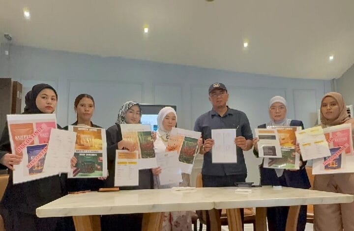 Eight people stand behind a table, each holding flyers and documents in a bright workshop room.